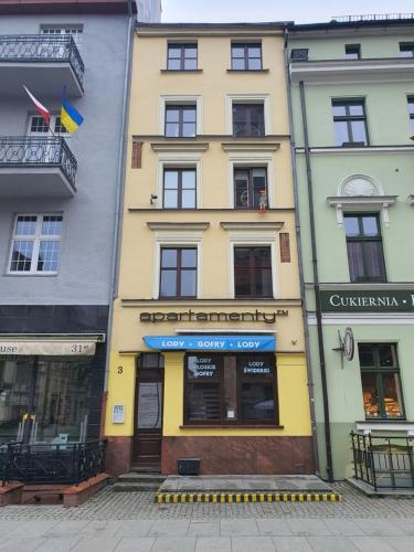un edificio amarillo con una tienda delante en Apartament z widokiem na pomnik Kopernika - Rynek Staromiejski, en Toruń
