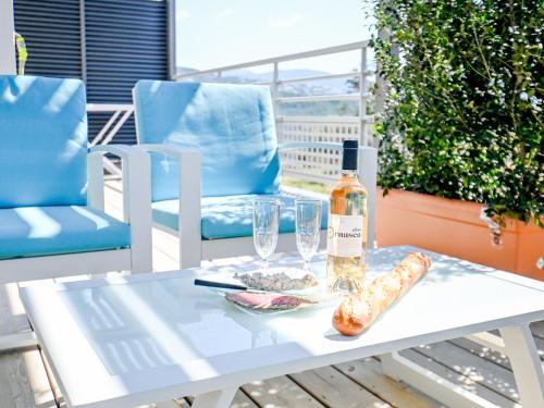 un tavolo bianco con una bottiglia di vino e due bicchieri di Les Vallons du Fort - Terrasse - Wifi - Clim a Porticcio