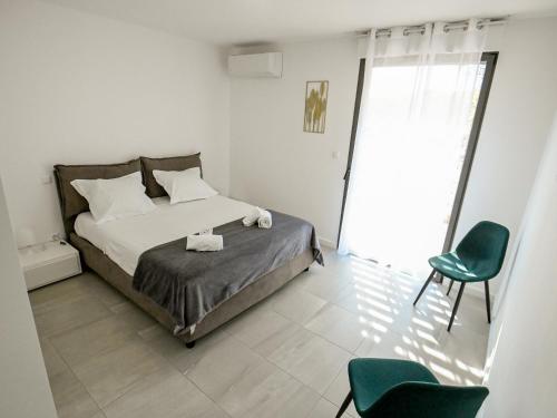 a bedroom with a bed and a green chair at Les Vallons du Fort - Terrasse - Wifi - Clim in Porticcio