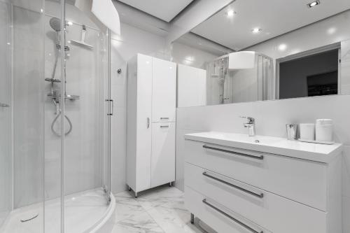 a white bathroom with a shower and a sink at APARTAMENTY MIERZEJA - MARINA, Kąty Rybackie, 100 m od Zalewu Wiślanego in Kąty Rybackie