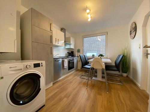 a kitchen with a washing machine and a table and chairs at Charmante Altbauwohnung an der Kesselschleuse 3 in Emden