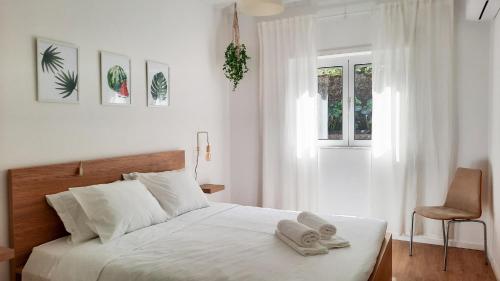 a white bedroom with a bed with towels on it at Lovely 2-bedroom apartment - near Braga city center! in Braga