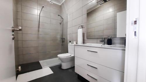 a white bathroom with a toilet and a sink at Lovely 2-bedroom apartment - near Braga city center! in Braga