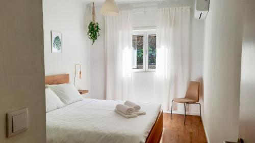 a white bedroom with a bed with towels on it at Lovely 2-bedroom apartment - near Braga city center! in Braga