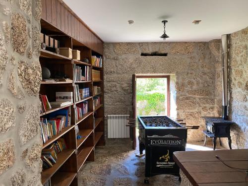 a room with a stone wall with bookshelves and a stove at Quinta Casa da Fonte in Vieira do Minho