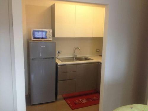 uma cozinha com um lavatório e um frigorífico com um relógio. em Comodo appartamento a pochi metri dal mare em Bibione