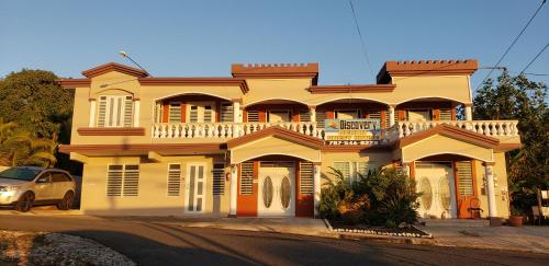a yellow house with a balcony on a street at Discovery Beach Apartments in Aguada