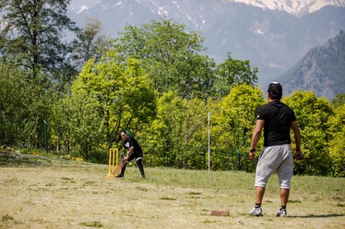 two men playing a game of cricket in a field at Anand Vardhan Resorts in Manāli