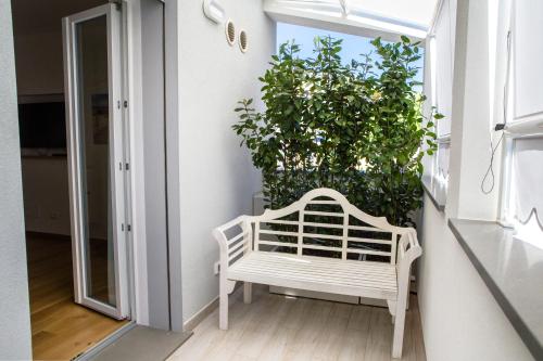 una panchina bianca su un balcone con una grande pianta di Attico Fronte Mare Residenza Matilde a Chiavari