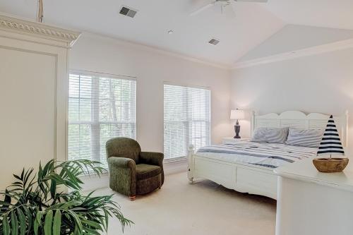 a bedroom with a bed and a chair and windows at Golfmaster D2 in Hilton Head Island