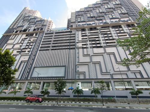 czerwony samochód zaparkowany przed wysokim budynkiem w obiekcie Imperio Melaka Family Suites by Jeffery Lam Home Management w Malakce