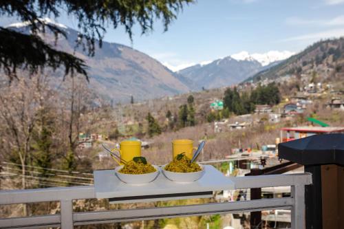 a table with two bowls of food on a balcony at Anand Vardhan Resorts in Manāli