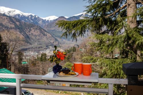 a table with a plate of food and a vase of flowers at Anand Vardhan Resorts in Manāli