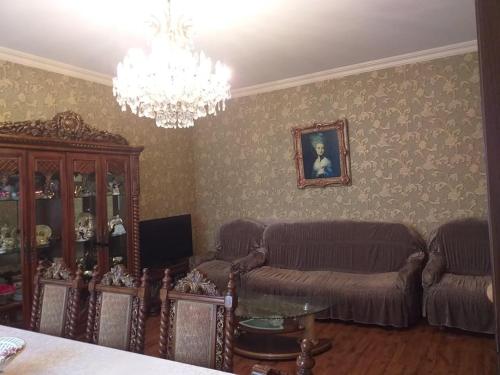 een woonkamer met een bank en een kroonluchter bij sweethouse in Tbilisi City