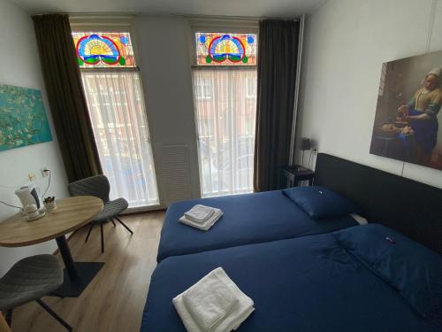 a bedroom with a bed and a table and stained glass windows at Hotel 't Sonnehuys in Scheveningen