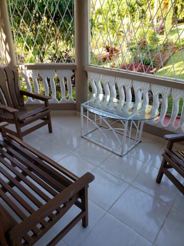 a porch with two benches and a glass table on it at Cliffe Ranch in Mandeville