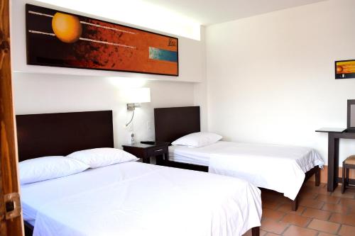 a hotel room with two beds and a painting on the wall at Chrisban Hotel Boutique in Buga