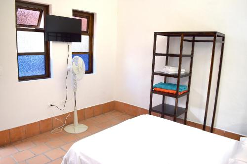 a room with a bed and a shelf and a fan at Chrisban Hotel Boutique in Buga