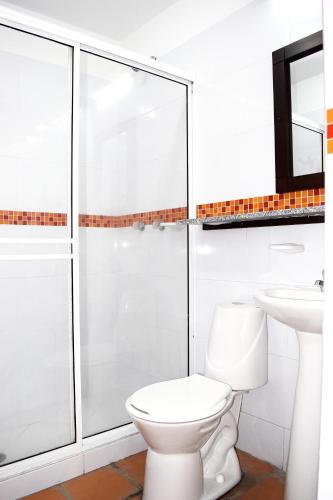a white bathroom with a toilet and a sink at Chrisban Hotel Boutique in Buga