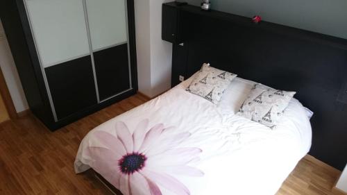 Un dormitorio con una cama blanca con una flor. en Apartamento en Corcubión en Corcubión