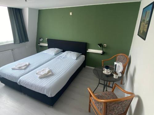 een slaapkamer met een bed, een tafel en een stoel bij Hotel 't Sonnehuys in Scheveningen