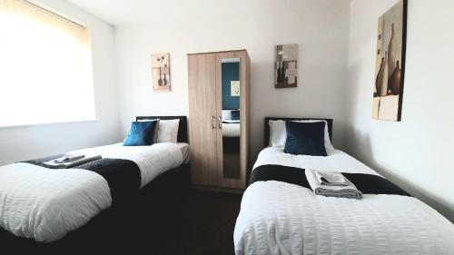 a room with two beds with white and blue pillows at Salford Ark Comfort Stays near Salford Royal and Trafford Centre in Manchester
