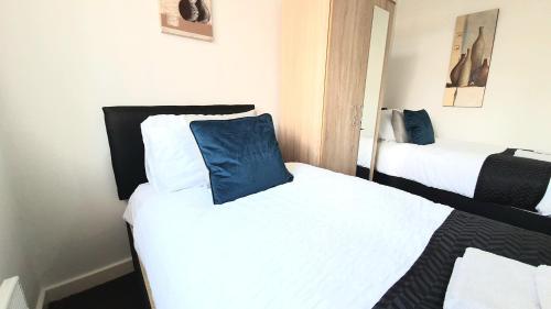 a bedroom with two beds with white and blue pillows at Salford Ark Comfort Stays near Salford Royal and Trafford Centre in Manchester