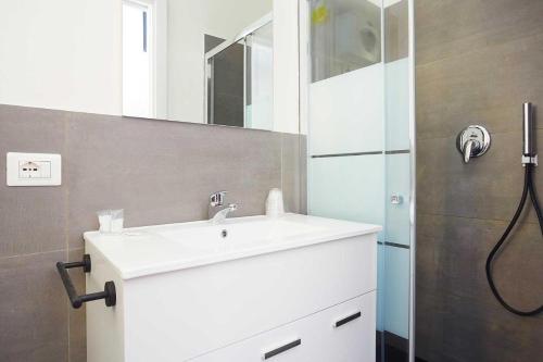 ein Badezimmer mit einem weißen Waschbecken und einer Dusche in der Unterkunft Stabilimento Lido Burrone in Favignana