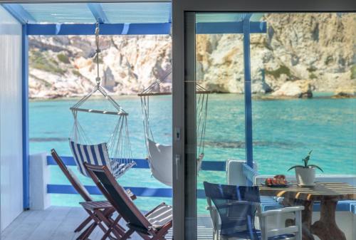 a porch with chairs and a table with a view of the ocean at Aquanis Anchored, sea front house, Firopotamos in Firopótamos