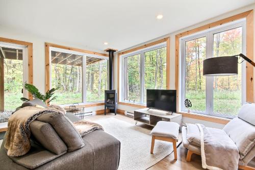 uma sala de estar com um sofá e uma televisão e janelas em Wellness Sutton cabin #267 Rez-de-chaussée em Sutton