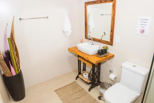 Un baño con lavabo, espejo e inodoro. en Suites da Lu, en Penha