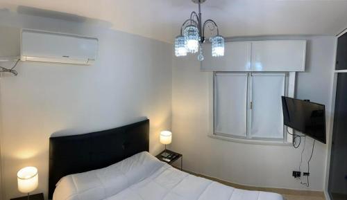 1 dormitorio con 1 cama, 2 luces y TV en Dpto Lyon en General Roca