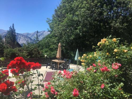LʼHuez的住宿－Chalet Martine，一个带鲜花、桌子和遮阳伞的庭院