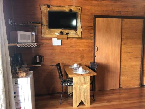 a small table with chairs and a television on a wall at Hospedagem Família Cruz in Urubici