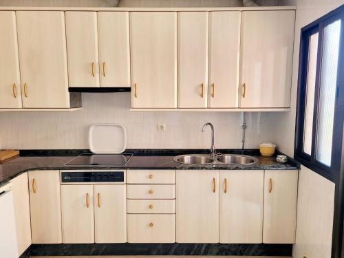 una cocina con armarios blancos y fregadero en A CONDA, en Arzúa