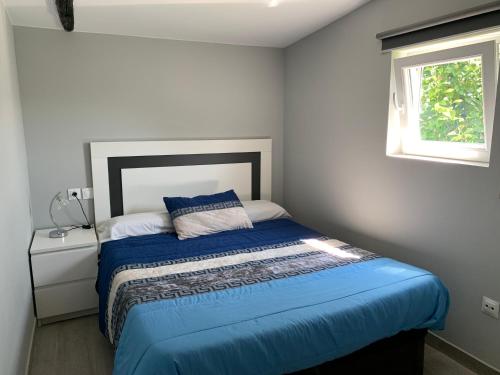 1 dormitorio con 1 cama con edredón azul y ventana en Casa rural La casilla de Ois-Betanzos-A Coruña, en Coirós