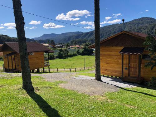 un par de cabañas de madera en un campo con árboles en Hospedagem Família Cruz, en Urubici