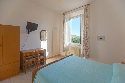 a bedroom with a bed and a desk and a window at Hotel Fiammetta in Quercianella