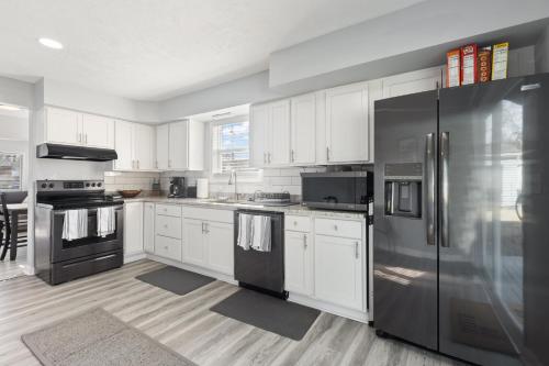 a kitchen with white cabinets and a stainless steel refrigerator at Entire Home Near MSU and Local Hospitals with Fast Wi-Fi & Dedicated Office in Lansing