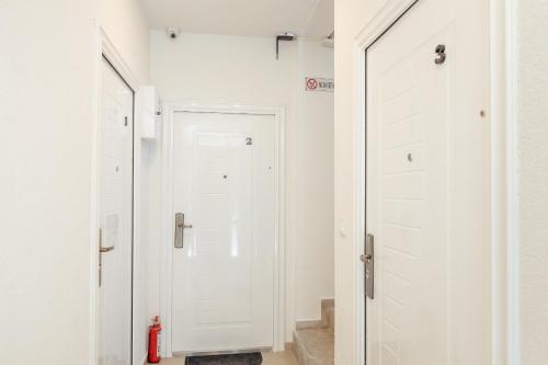 a hallway with white doors and a fire extinguisher at Magnolija apartmani in Igalo