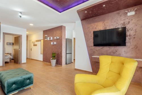 a living room with a yellow chair and a flat screen tv at Magnolija apartmani in Igalo