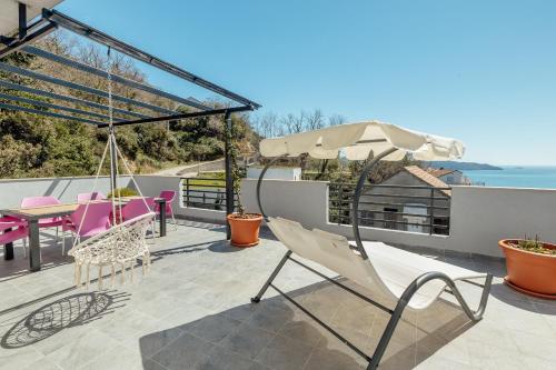 a patio with chairs and a table and an umbrella at Magnolija apartmani in Igalo
