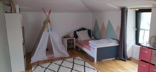 - une chambre avec un lit et une tente de jeux dans l'établissement Maison de Famille, grand jardin et piscine fermée, à Fontenay-le-Comte