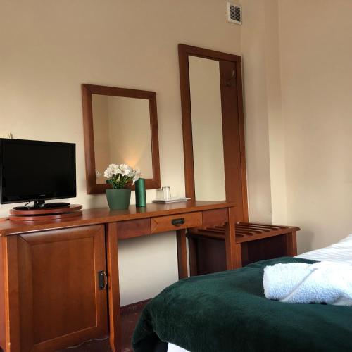 a bedroom with a desk with a television and a mirror at Willa Anna - Pokoje Gościnne in Goczałkowice-Zdrój
