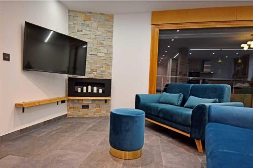 a living room with a blue couch and a flat screen tv at Casa Rural La Cueva del Agua in Fuentetoba