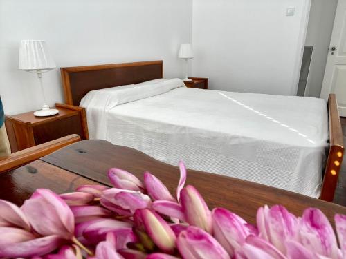 a pile of pink flowers in a room with a bed at Casa Às Sete in Angra do Heroísmo