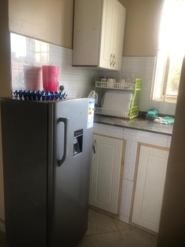 a kitchen with a black refrigerator and white cabinets at Brooks apartments in Kampala