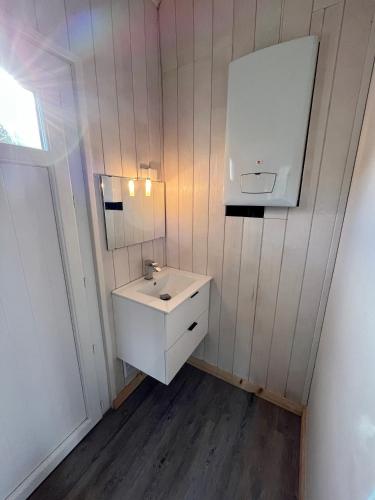 une salle de bain avec un lavabo blanc et un miroir dans l'établissement Villa Petit-Père - à 400m de la plage, à Taussat-les-Bains