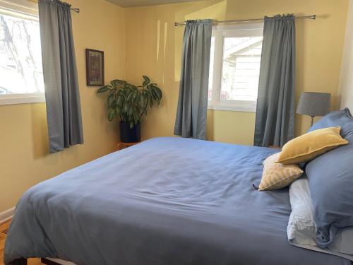 a bedroom with a large bed with blue sheets and windows at Turnagain Guest House in Anchorage