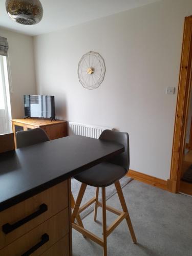 a desk with two chairs and a clock on the wall at The Studio in Drumnadrochit